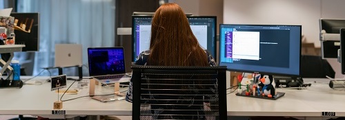The back of a woman who is working at a computer in an office
